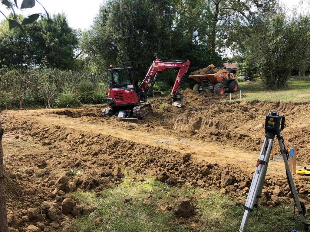 Terrassement au laser avec un belle a chenille et évacuation de la terre au dumper bassin de baignade piscine naturelle biologique