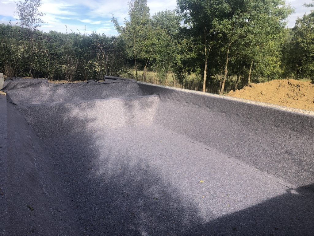 Pose de géotextile sur le terrassement d'un bassin de baignade piscine naturelle