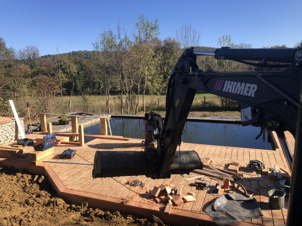 Terrassement de finition autour d'une piscine naturelle bassin de baignade et terrasse en bois avec une belle a chenille